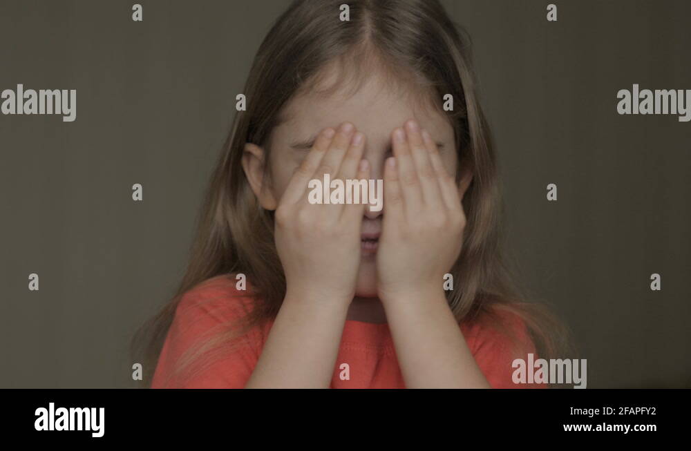 Cute little girl open her face with hands. Girl looks and is surprised ...
