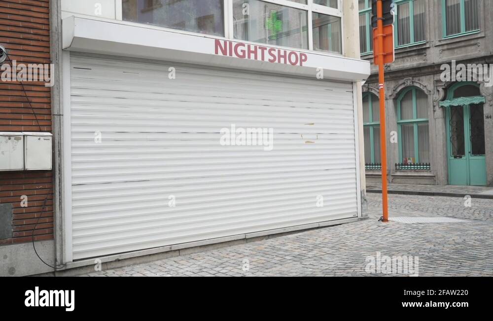 A closed Night shop with people passing in front. The white window