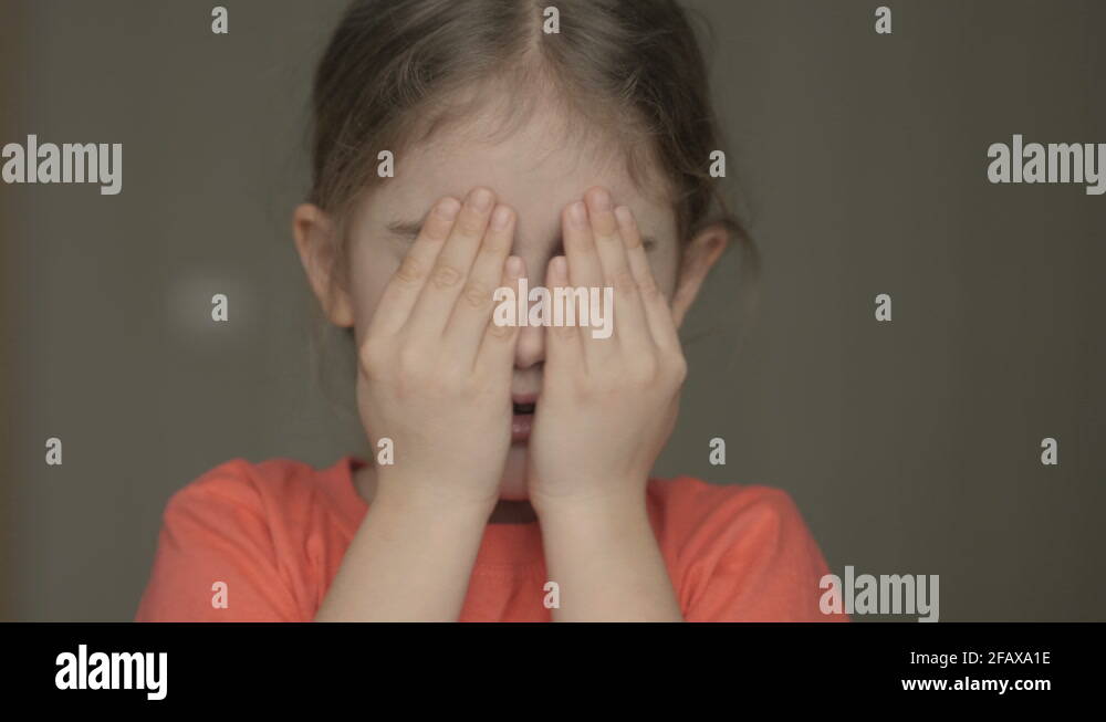 Cute little girl open her face with hands. Girl looks and is surprised ...