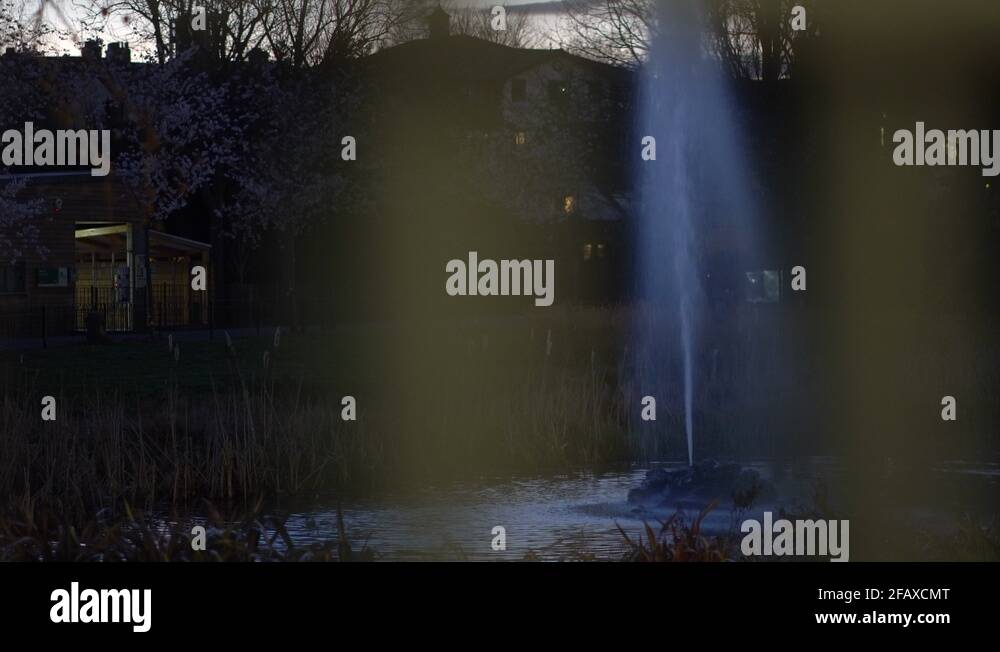 Night at the park, water reflection of a fountain from a gate, urban ...
