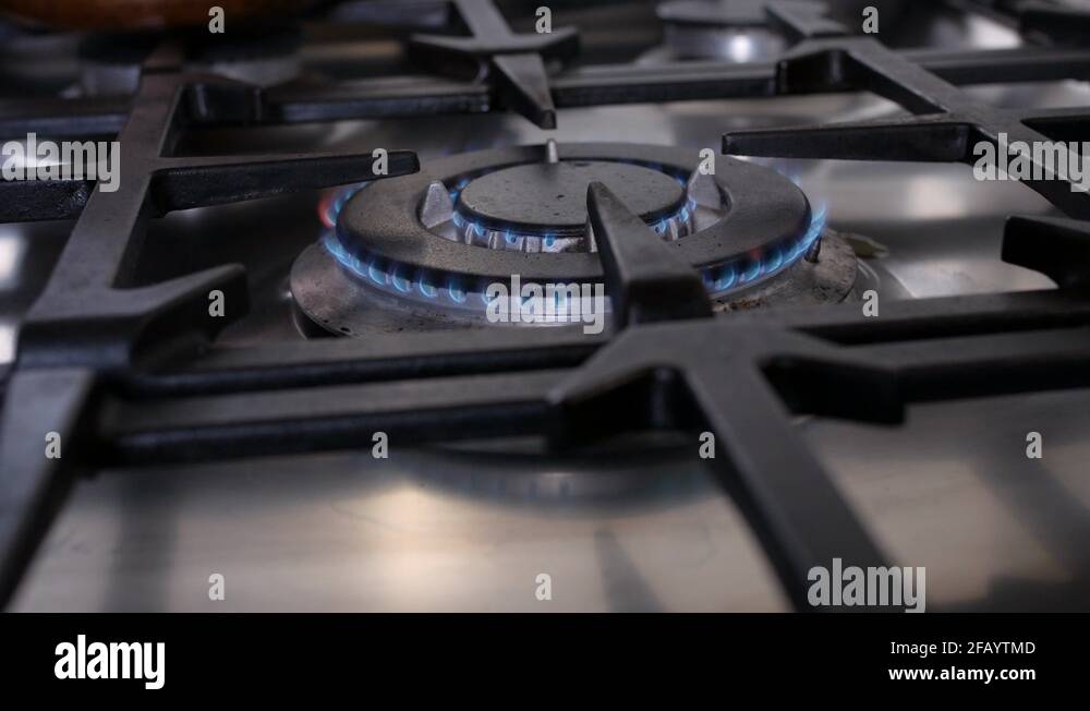 Close shoot of a lit burner with blue flames on a steel gas stove going