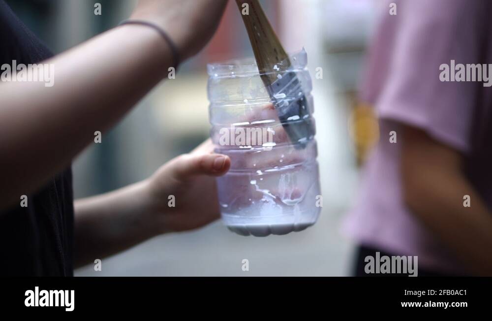 Bokeh Linked Brushing Girls Pouring Water Into a Cut Off Plastic Bottle With Glue Stock Video