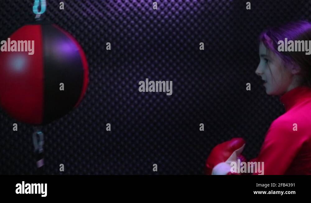 Little girl in red boxing gloves punching and kicking double end