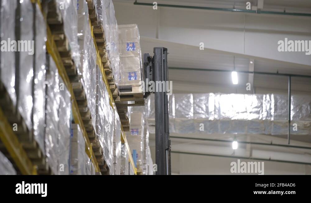 Warehouse worker driver loading cardboard boxes by forklift stacker ...