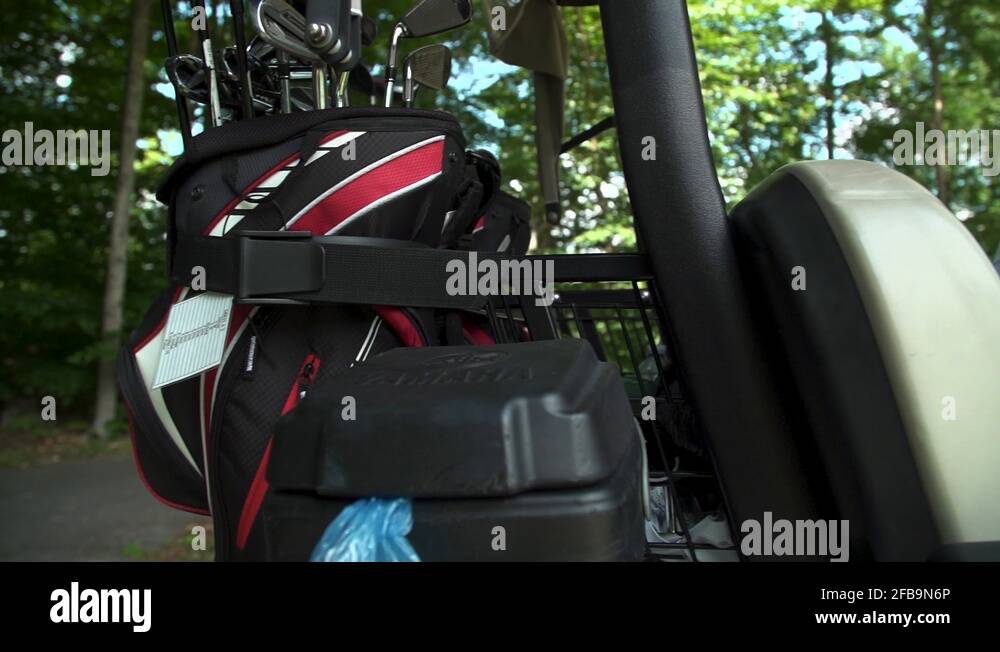 Golf bag on back of golf cart while golfer sits in front seat Stock