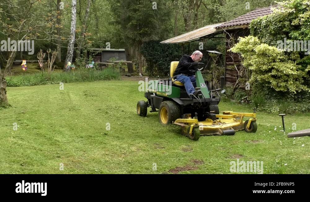 Pan Man riding lawn mower, cutting grass around tree in garden