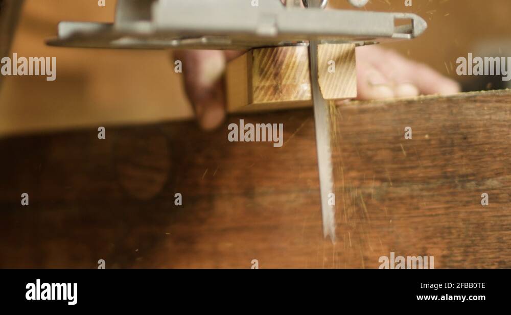 Jig saw cuts rounded corner on hardwood piece with flurries of saw dust