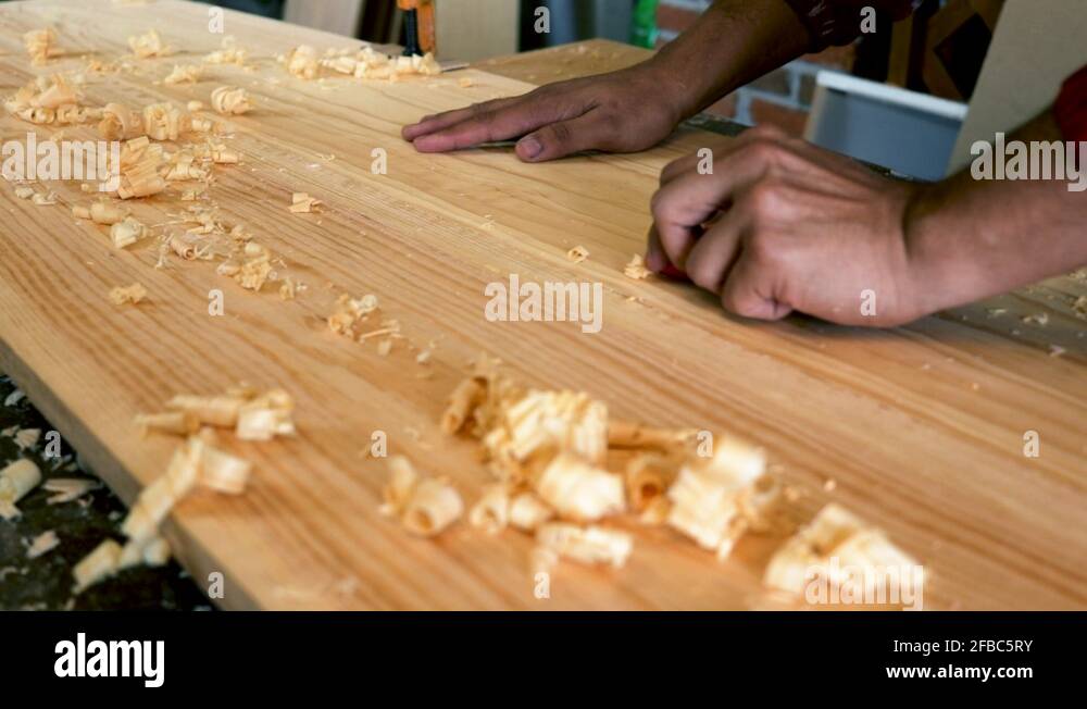 Side view. Male hands planing a wood board. wood shavings on a plane
