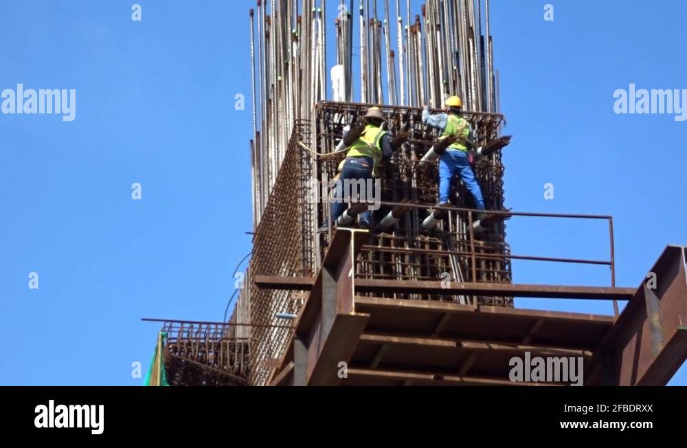 Construction workers working at height fabricating steel reinforcement ...