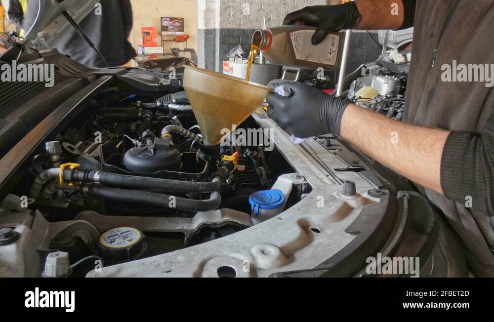 Pouring new oil from bottle into engine using a funnel in a