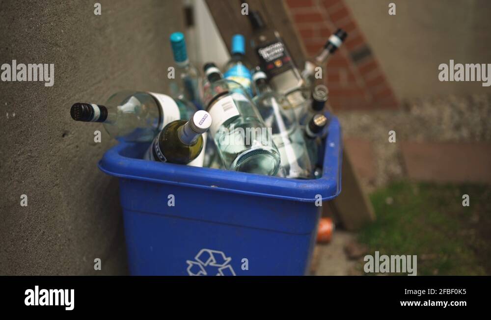 Slow push in on many wine and liquor bottles in a recycling bin Stock