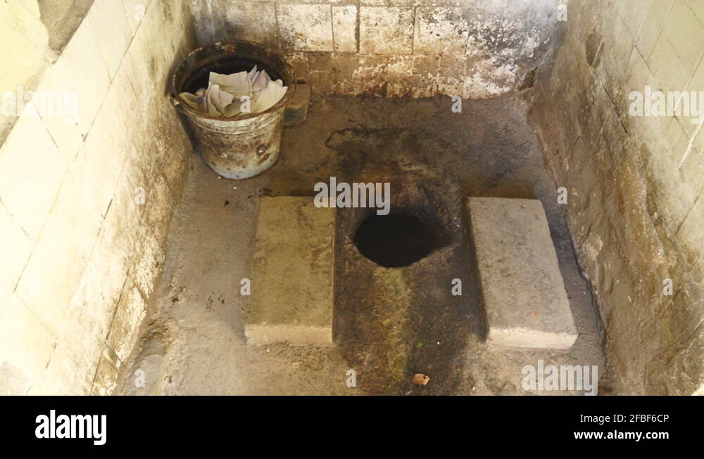 Dirty public outhouse with squat toilet and pit latrine first person