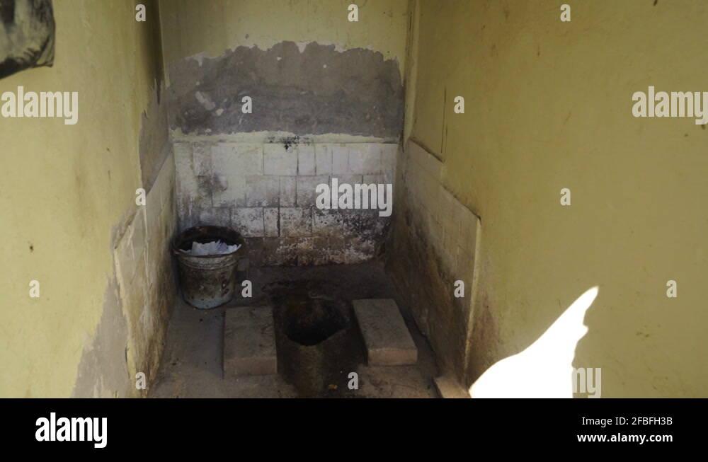 Dirty public outhouse with squat toilet and pit latrine first person