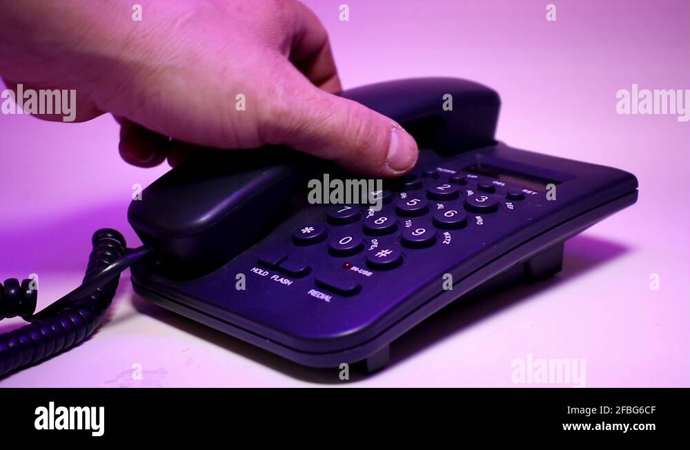 CloseUp Of Black Wired Button Phone. Man’s Fingers Dialing Random