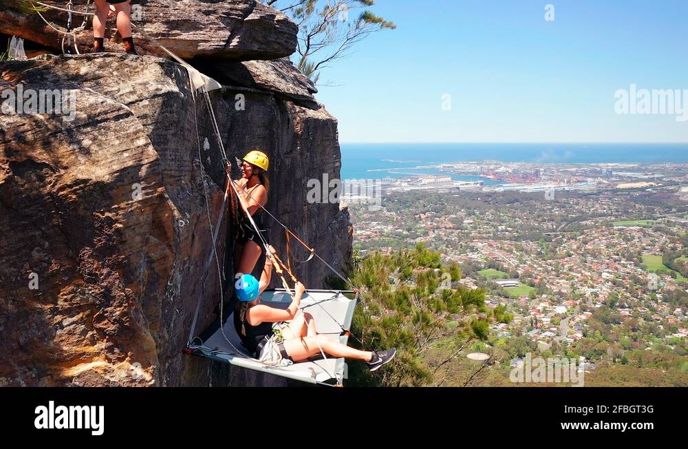Three rock climbers installing a hanging bed outside on Australian