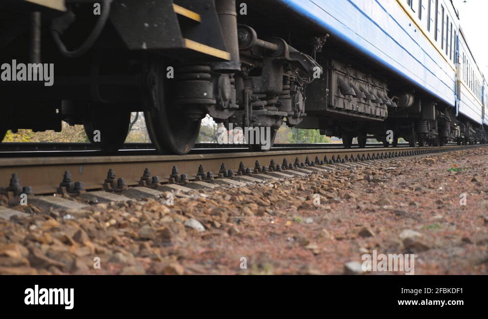 Close up spinning steel wheels of the train moving along the rail track ...