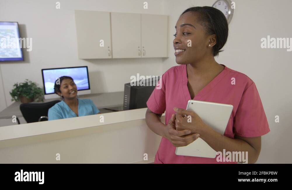 Two nurses talking, one turns and walks down hospital hallway, tracking ...