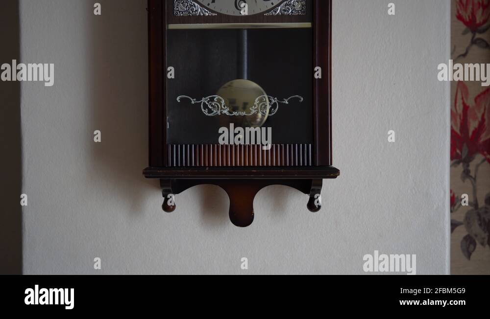Pendulum swinging on an old pendulum clock. A steady face on shot. Loop