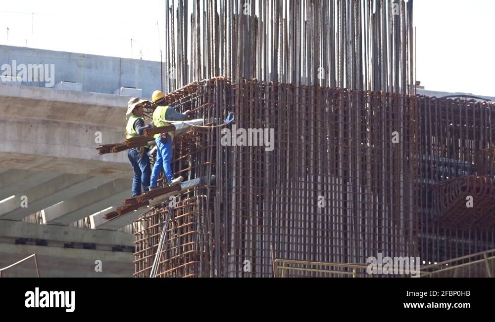 Construction workers working at height fabricating steel reinforcement ...