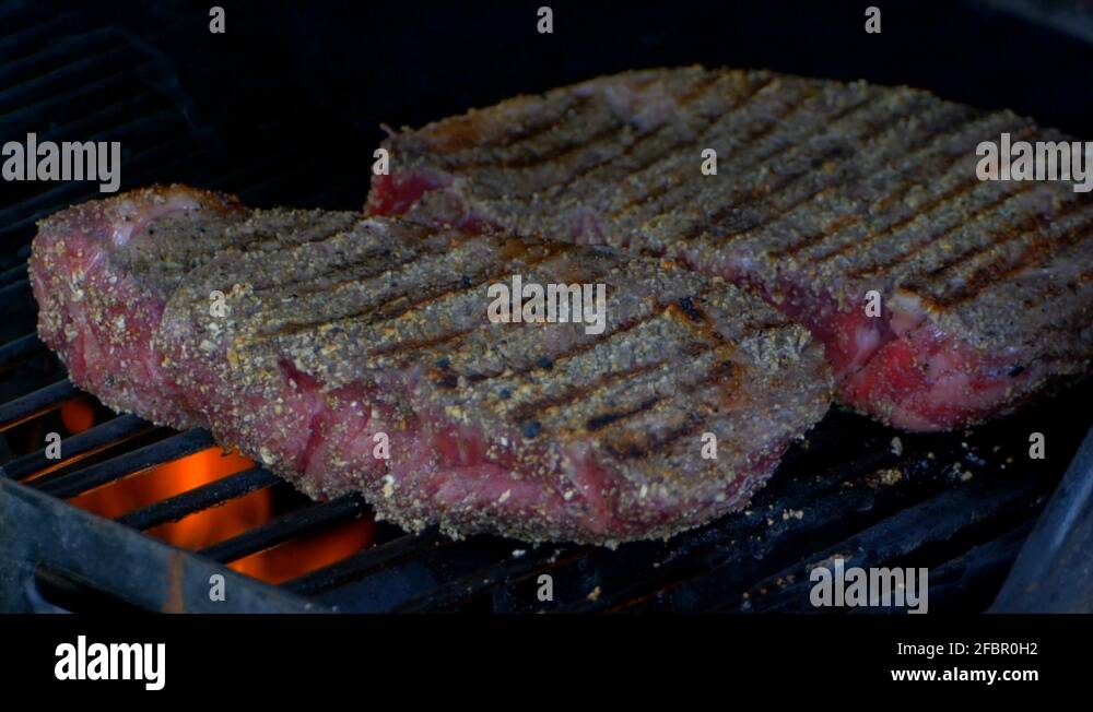 Two thick and juicy rib eye steaks are covered as a grills lid is