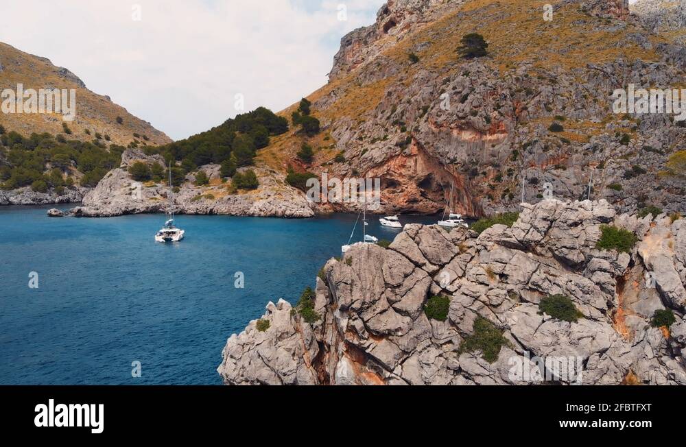 Drone flying around a rock showing white ships anchoring in a peaceful ...