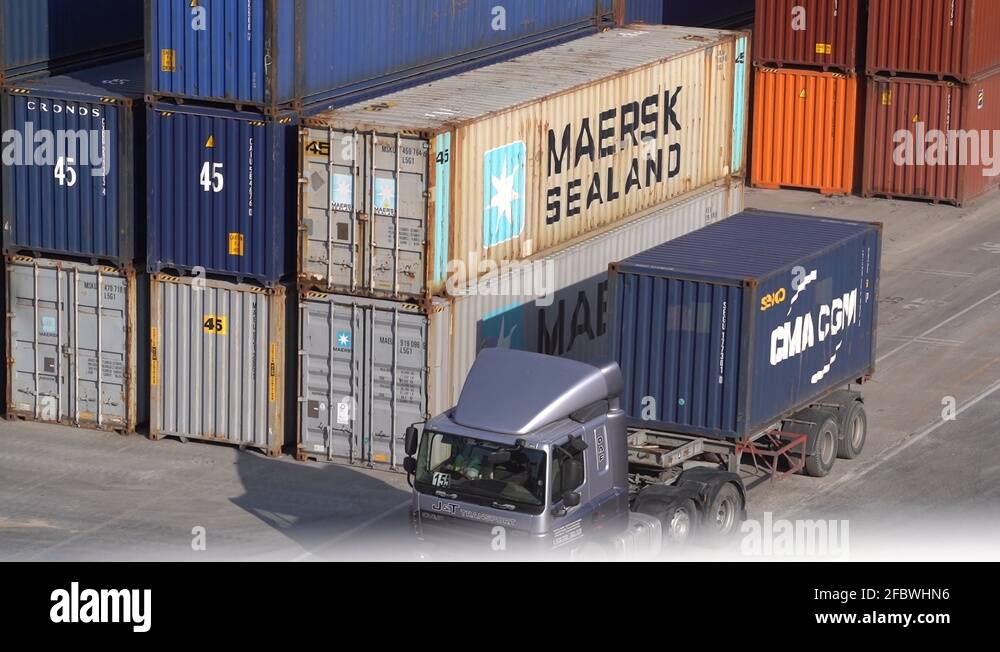 Truck leaving with shipping container, revealing a Seaport with cargo ...
