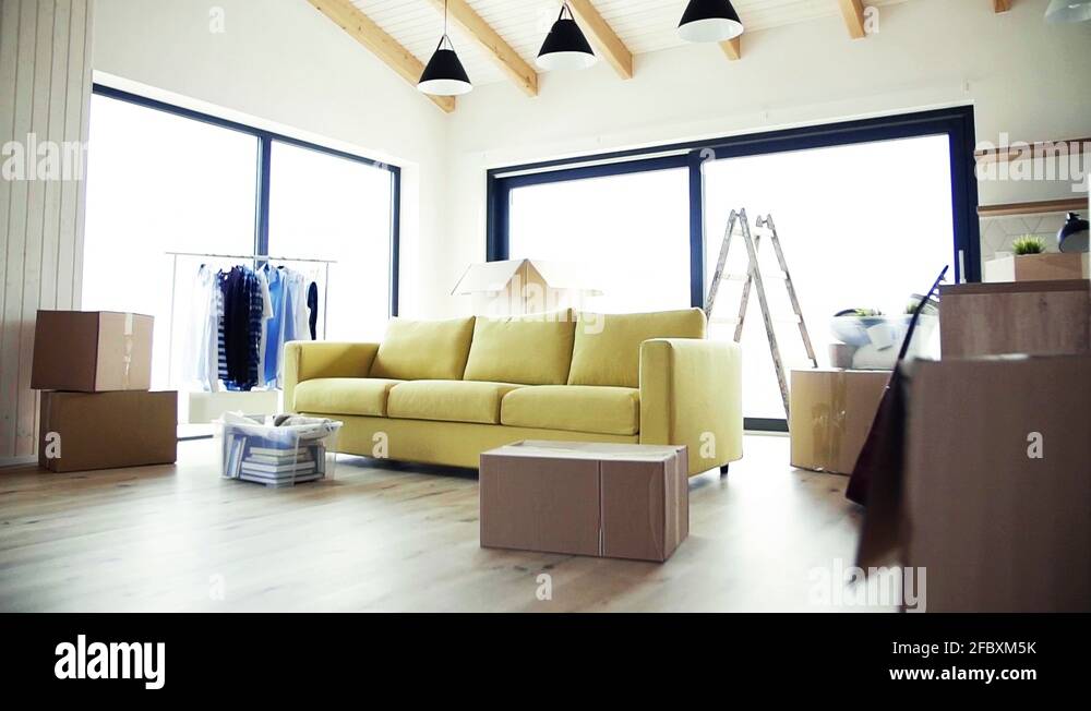 Moving boxes, sofa and clothes rack on the floor in new home. Slow