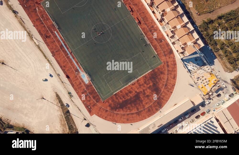 Cinematic bird eye view of football soccer stadium with athletic tracks