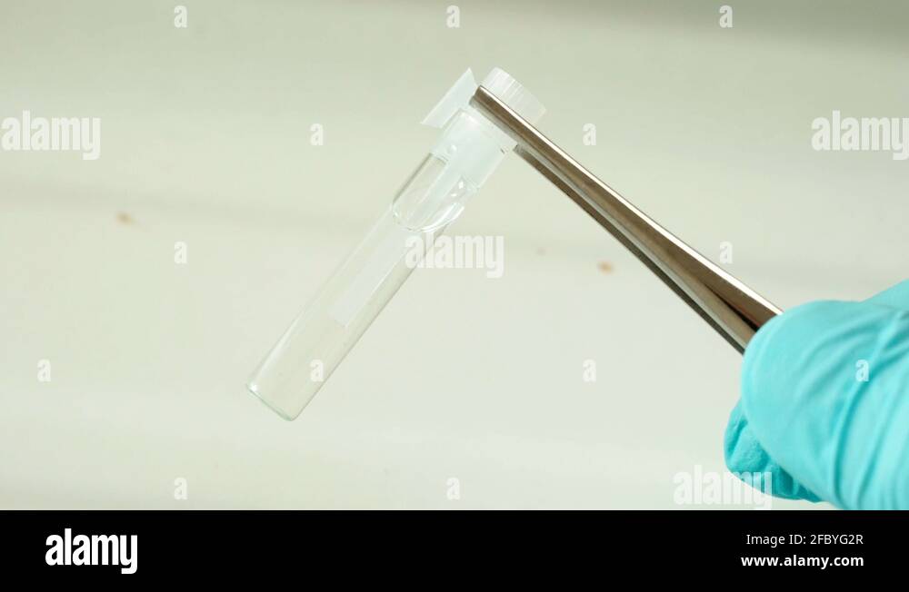 Hand holding tweezers deadly liquid ampoule FBI forensic drug testing