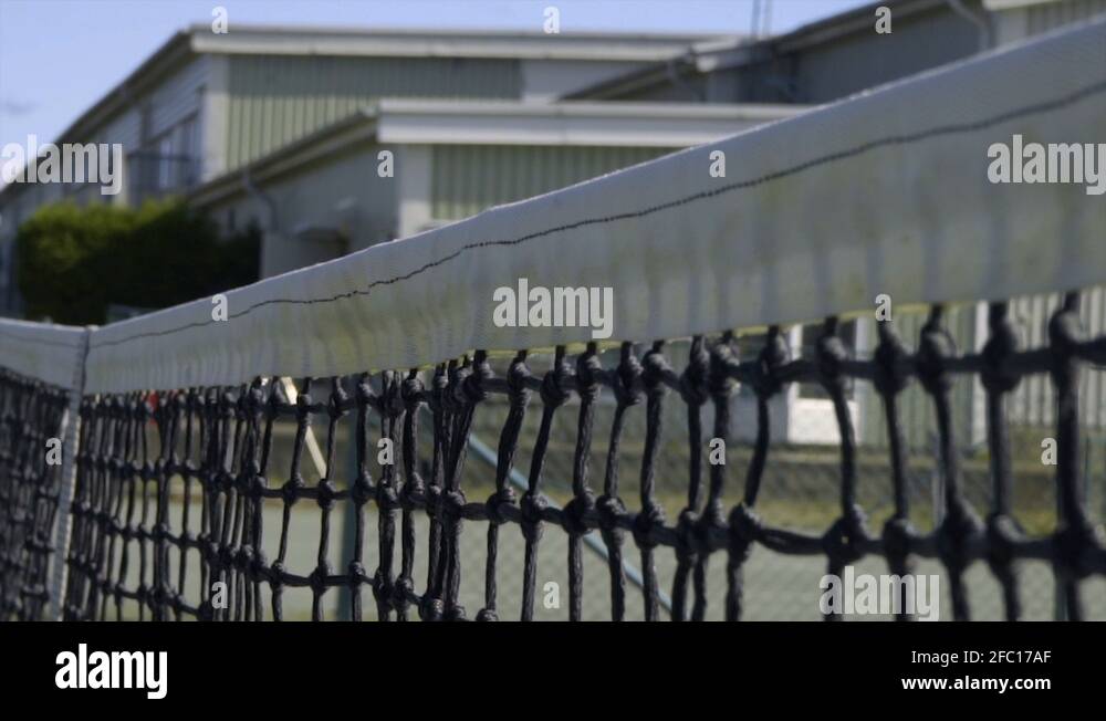 A tennis ball hits the net in a serve in slow motion. bounces down and