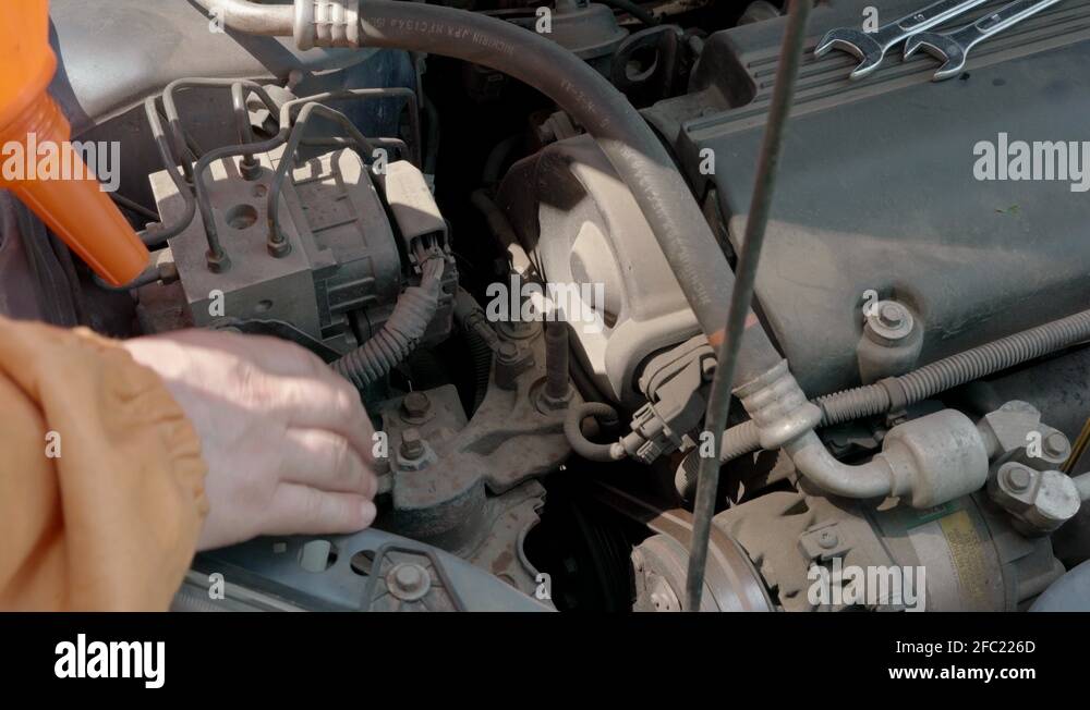 Auto mechanic removing the car engine windshield washer fluid reservoir