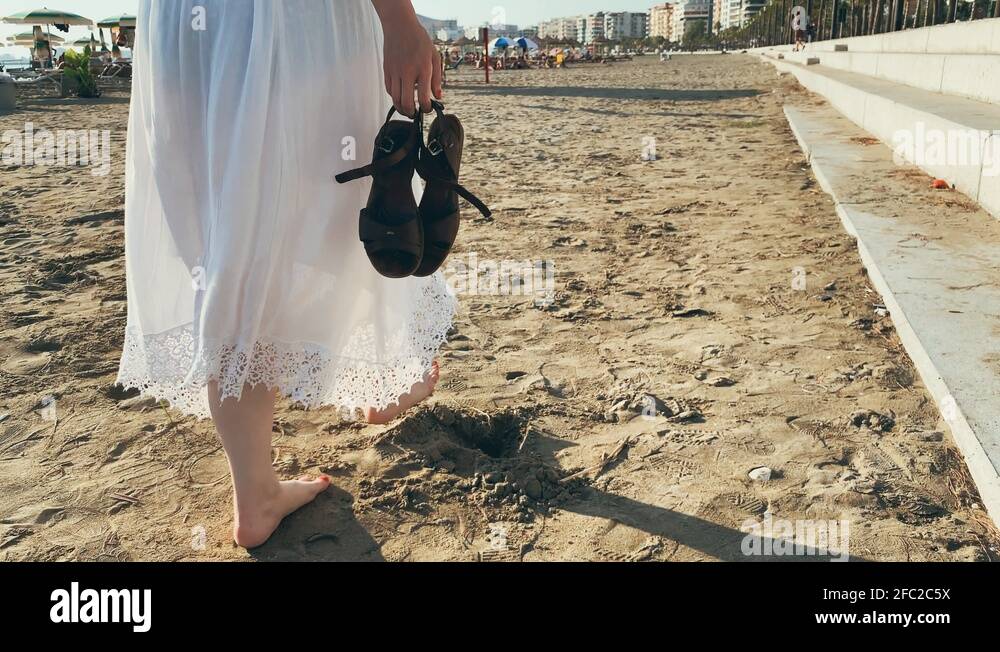 Young woman in white dress walking on the beach barefoot 4k Stock Video ...