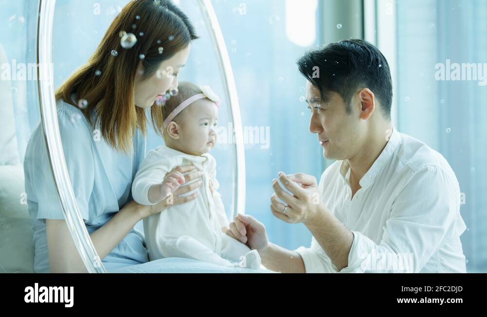 Adorable Chinese baby enjoying curious floating soap bubbles Stock