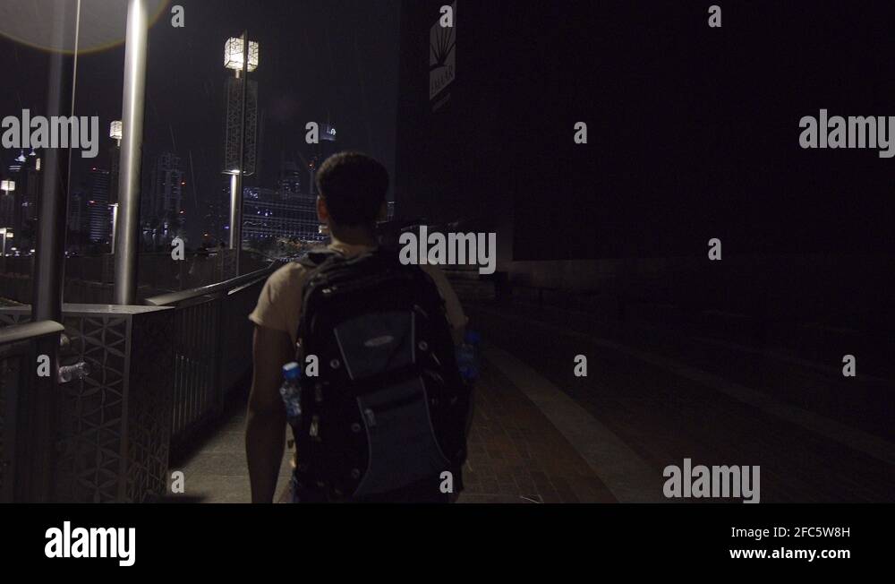 Back view of a young man walking at city street in Dubai at night Stock ...
