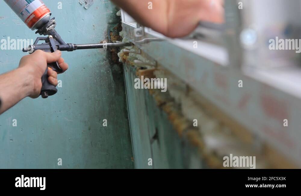 Worker is applying polyurethane foam to fill gap between sash and