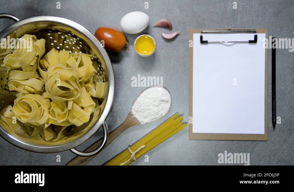 Pappardelle pasta on a water drainer spinning, with ingredients, spoon