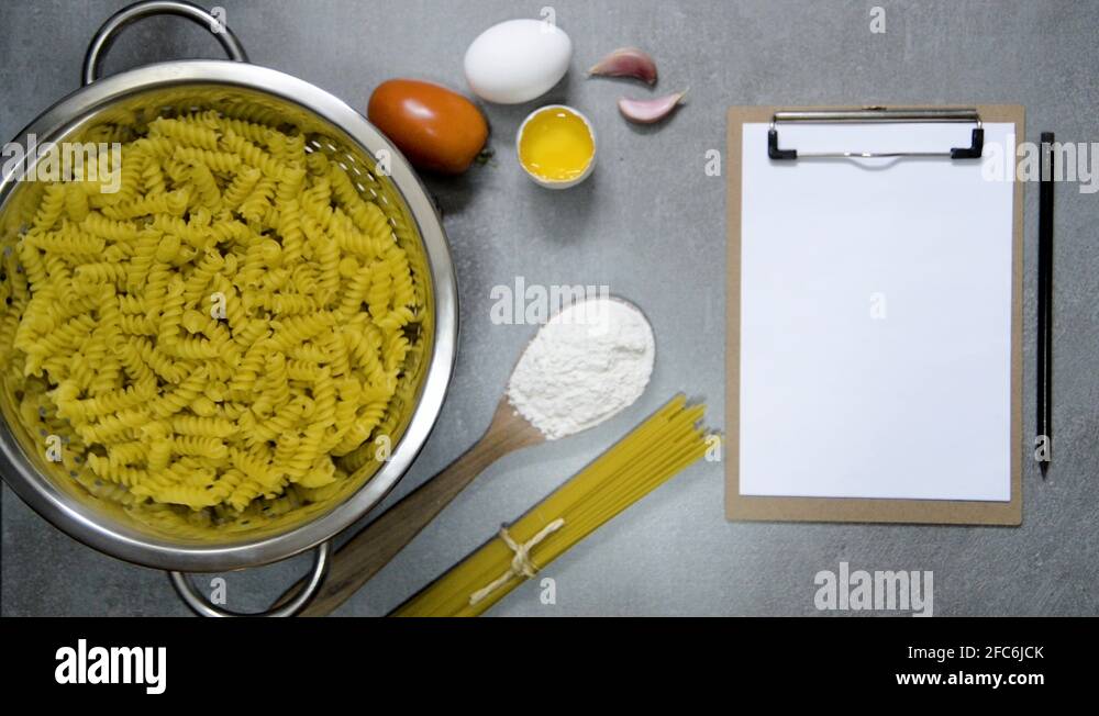 Fusilli pasta on a water drainer spinning, with ingredients, spoon and