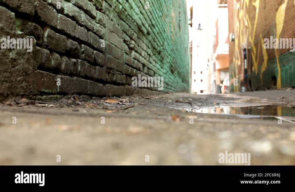 Man running through alley steps in puddle Stock Video Footage Alamy