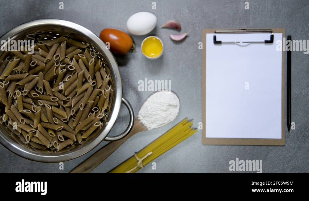 Penne whole pasta on a water drainer spinning, with ingredients, spoon