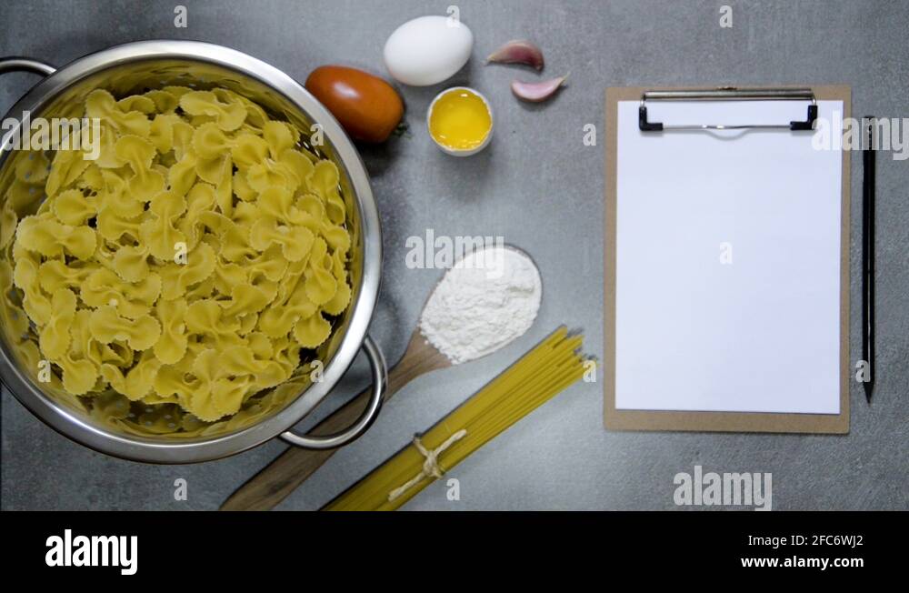 Farfalle pasta on a water drainer spinning, with ingredients, spoon and