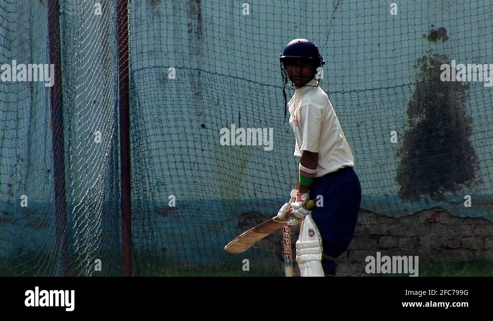 A young indian boy practicing cricket wearing cricket wearing whites