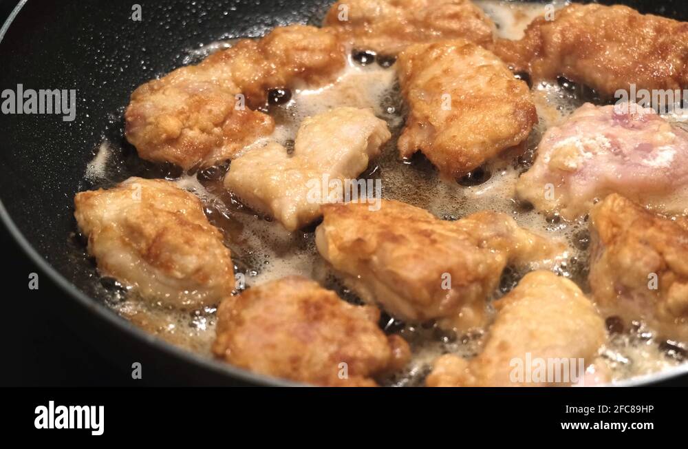 Close up on chicken nuggets cooking in hot oil in a frying pan, 4K