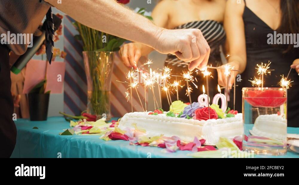 People lighting sparkling candles on birthday cake at a celebratory