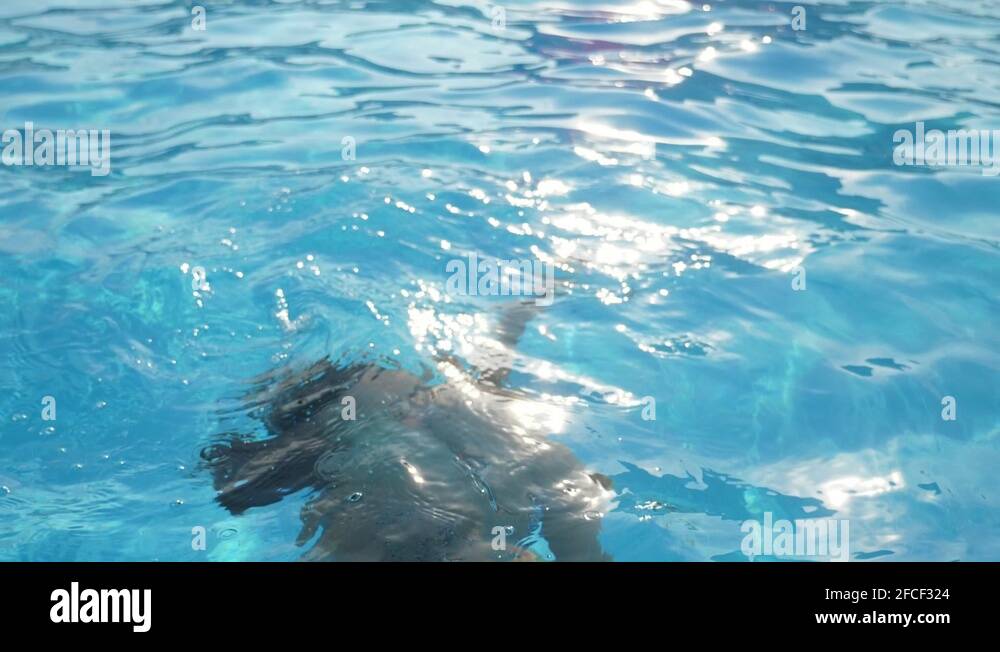 Young woman coming out of water keeping her nose in swimming pool in