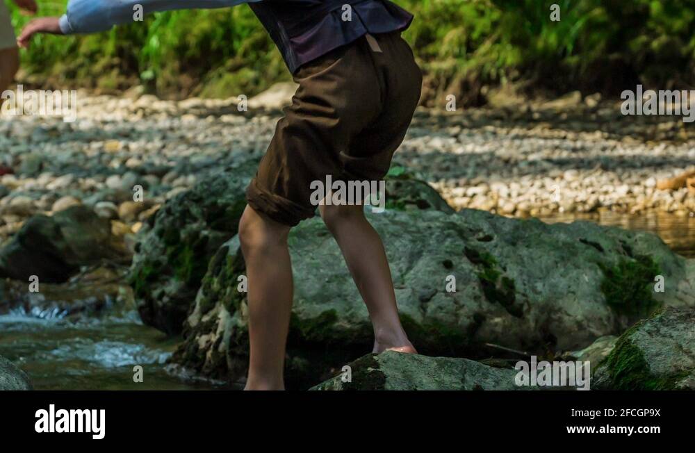 Boy slips and he falls over a rock into the water Stock Video Footage