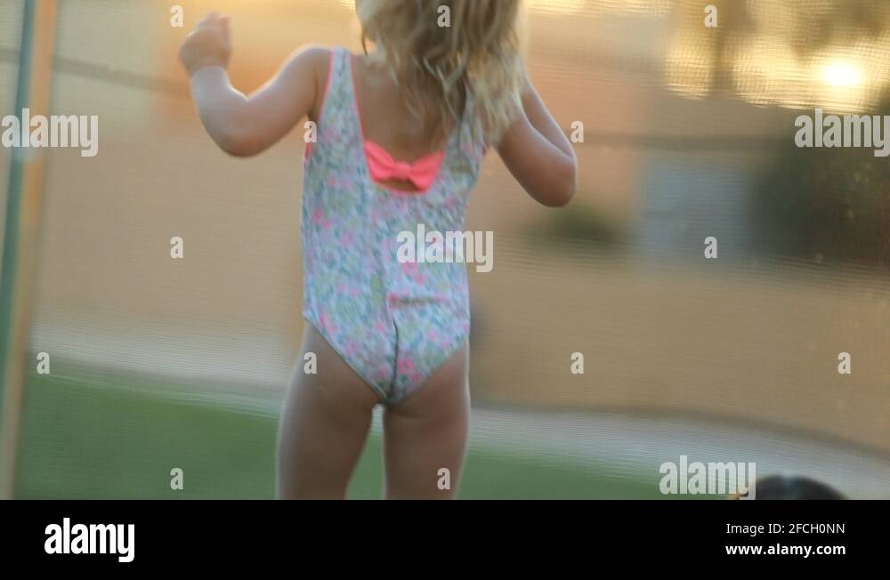 Happy Little girl bouncing up and down on trampoline outside feeling joy Stock Video Footage Alamy