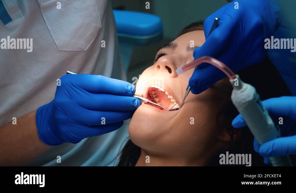 dentist in gloves sealing patient woman's teeth using dental mirror