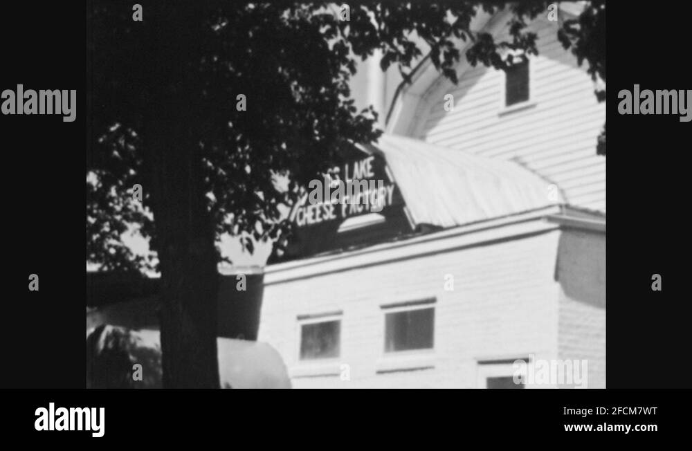 1940s Cheese factory sign on building. Man loads wheels of cheese into