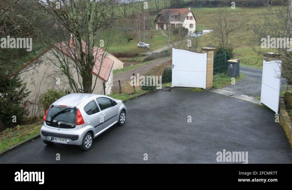 Little grey car driving off on a wet day in rural french driveway home