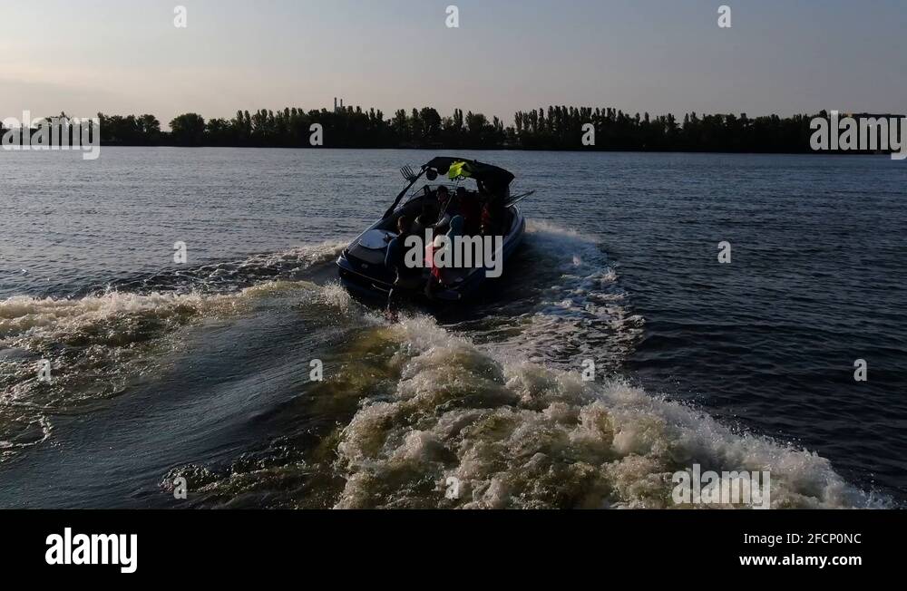 Wake surfer is dropping the rope and surfing on a wake behind the boat